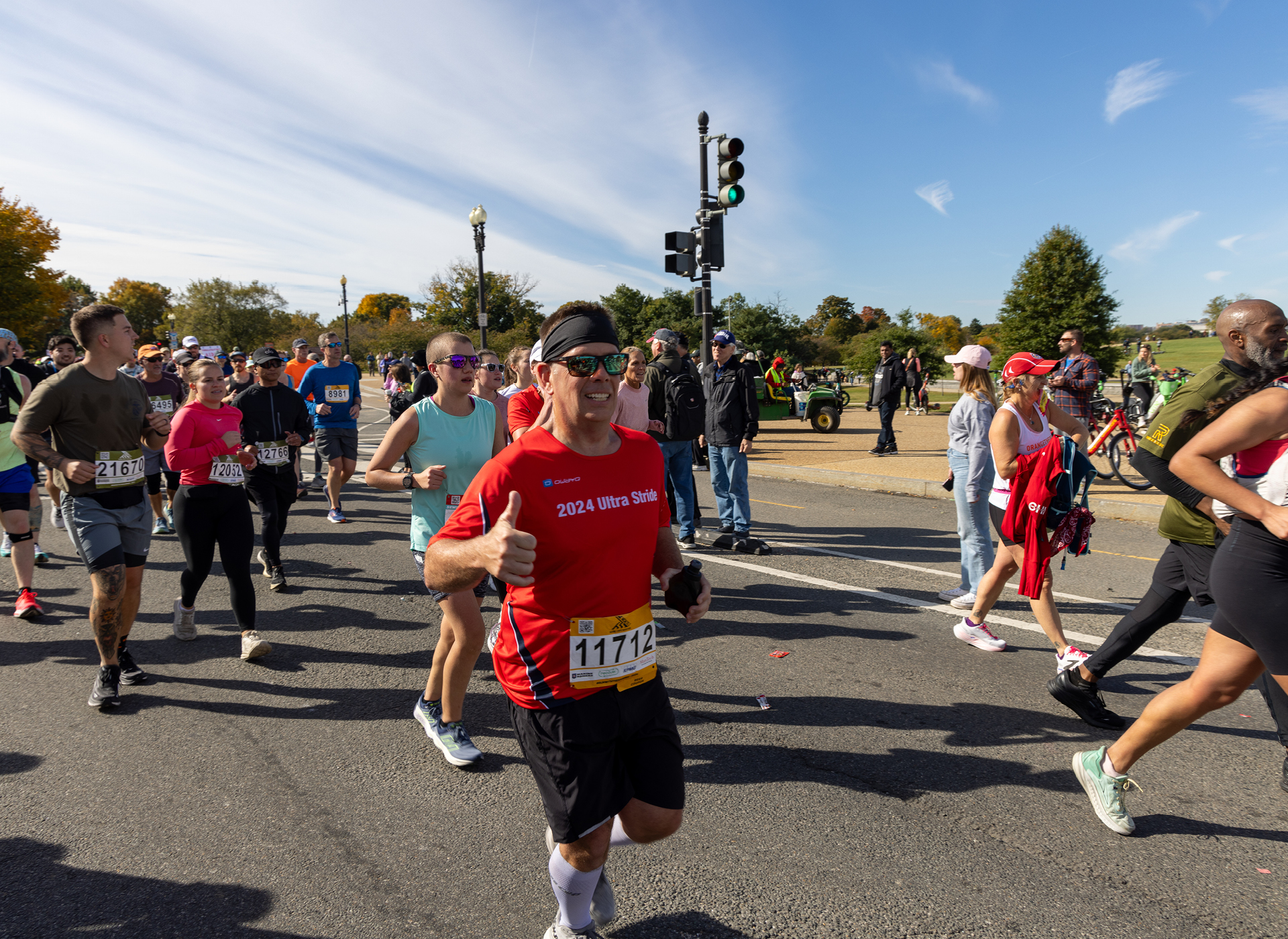 person in red shirt runs with a crowd of people in a marathon