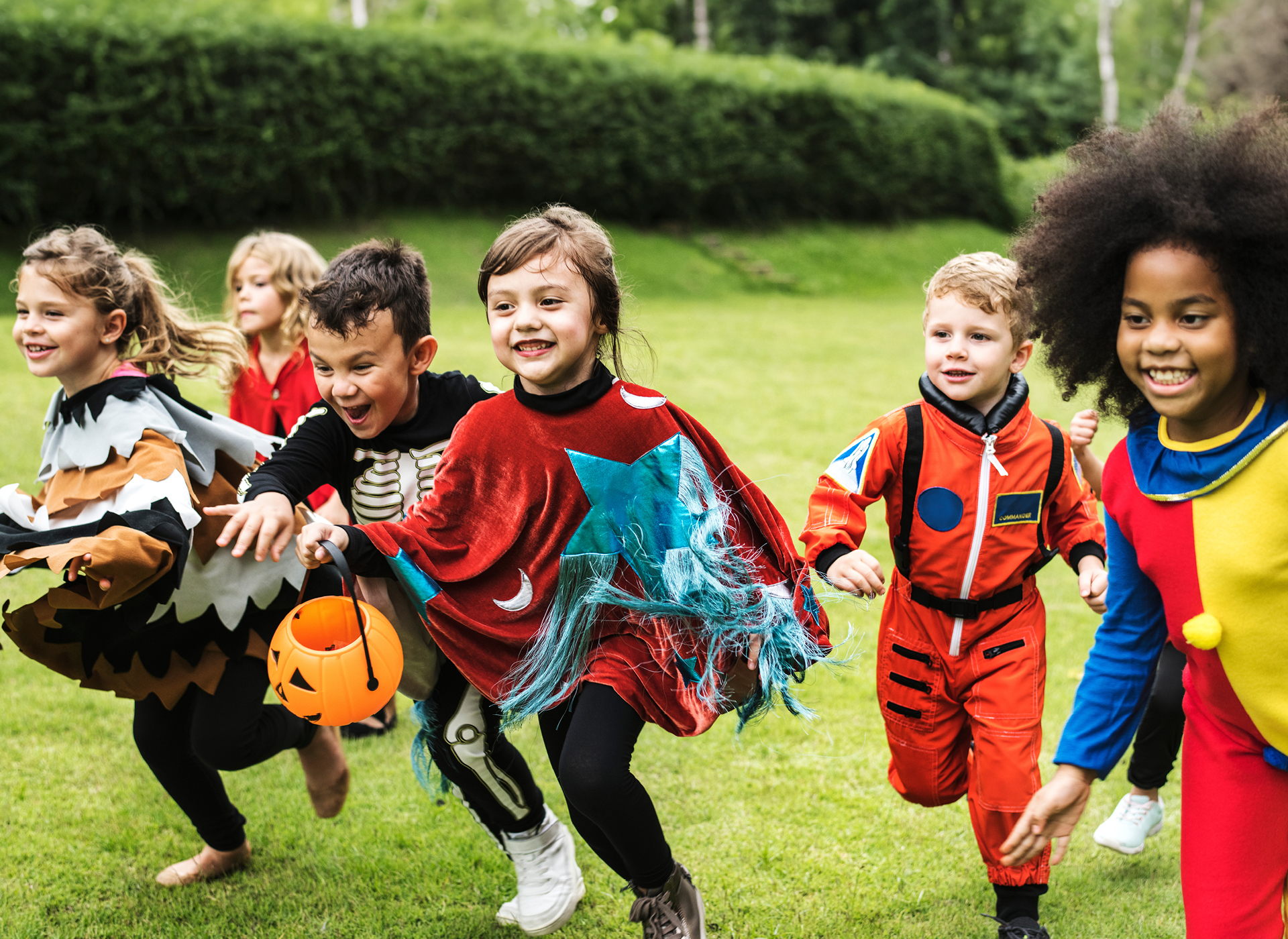 six kids in costumes running through a field