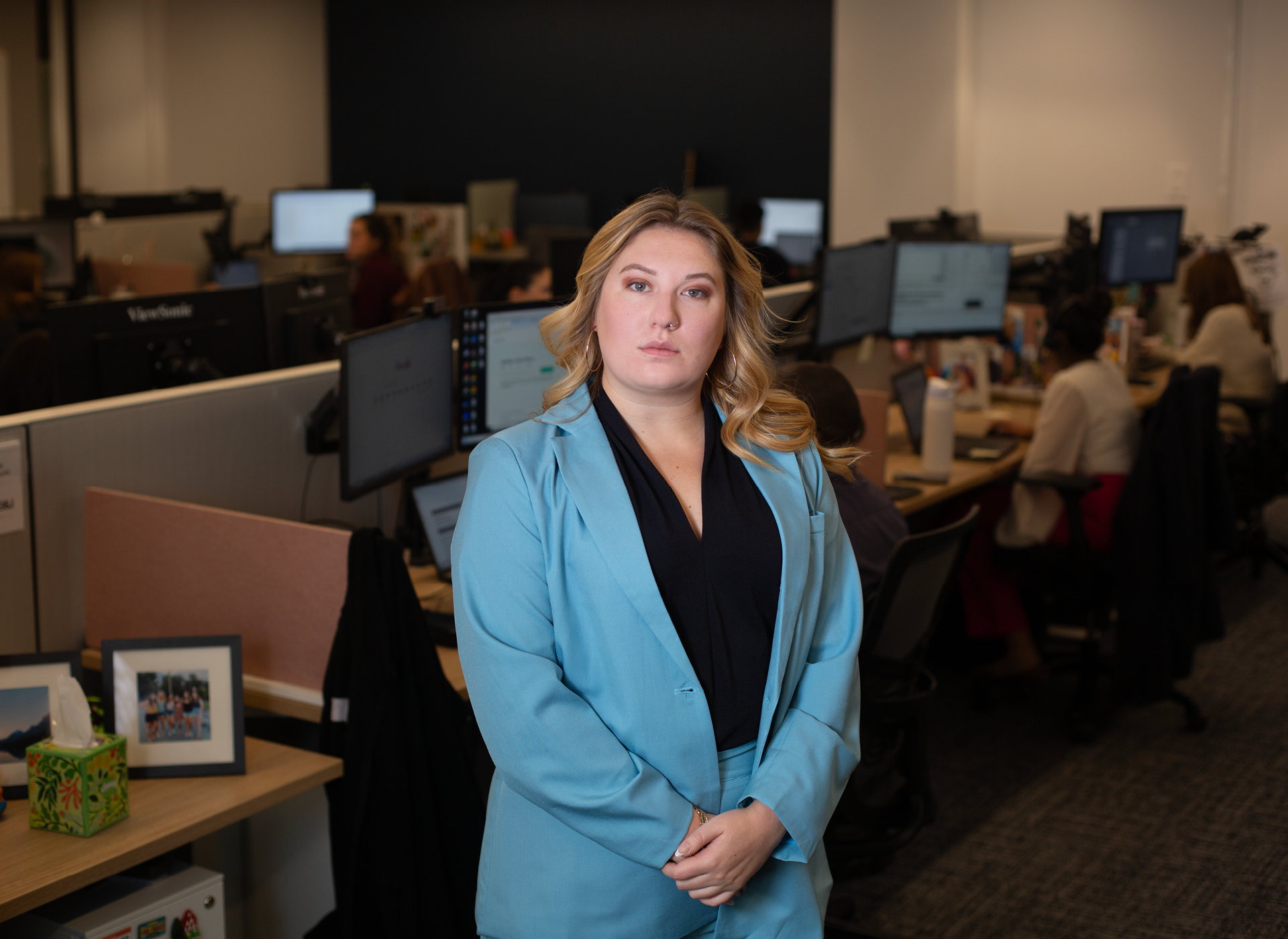 hayley stands in ncmec office wearing black top, light blue jacket. hair is long and blonde.